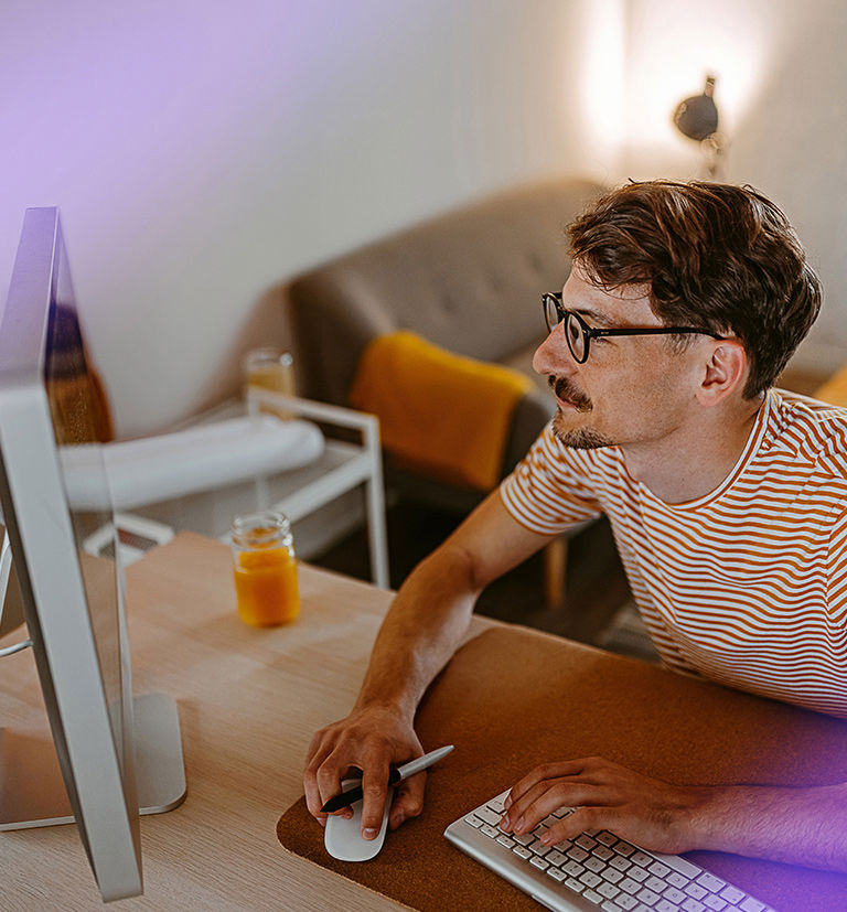 Man working at a desktop computer in a home office for TP.