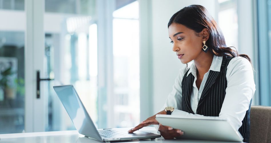 Young business professional working on a laptop in a modern work setting.