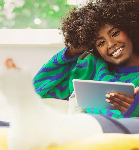Afro descendant woman with a leg cast using a tablet, reflecting trusted digital healthcare support.