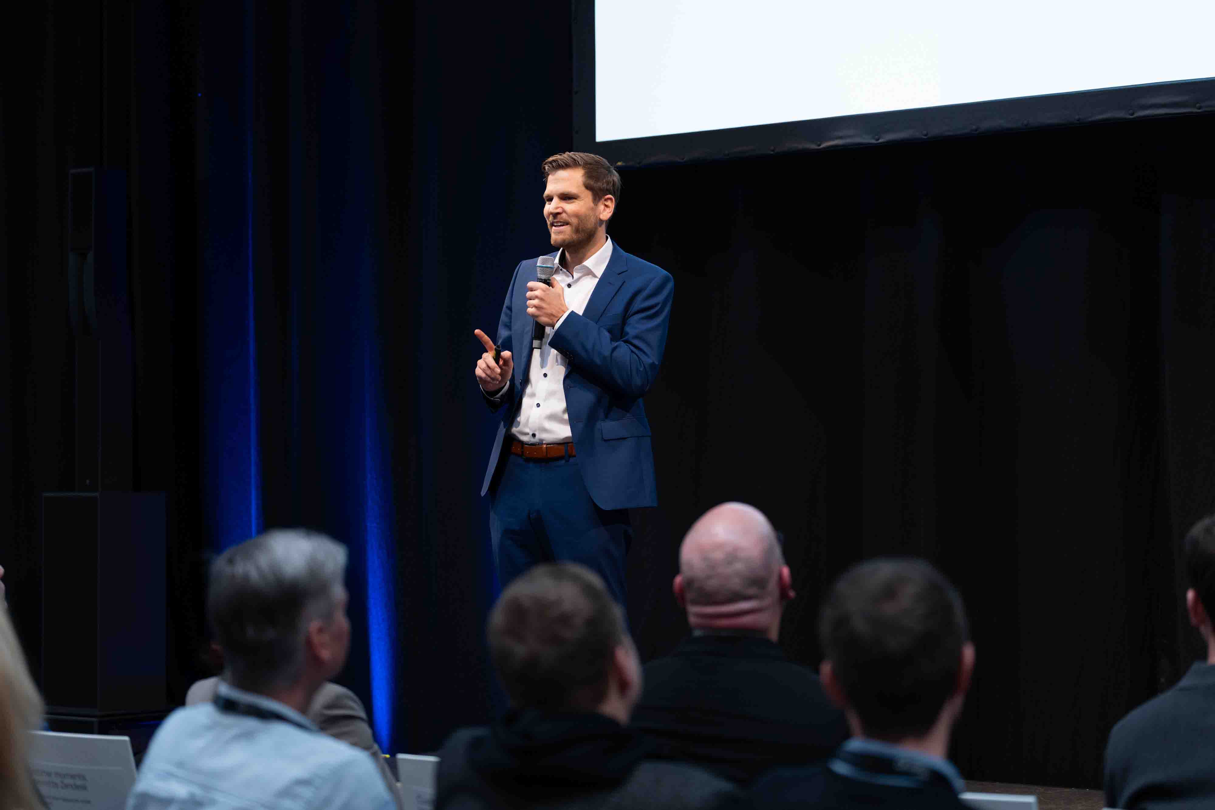 Professional speaking on stage at a corporate event.
