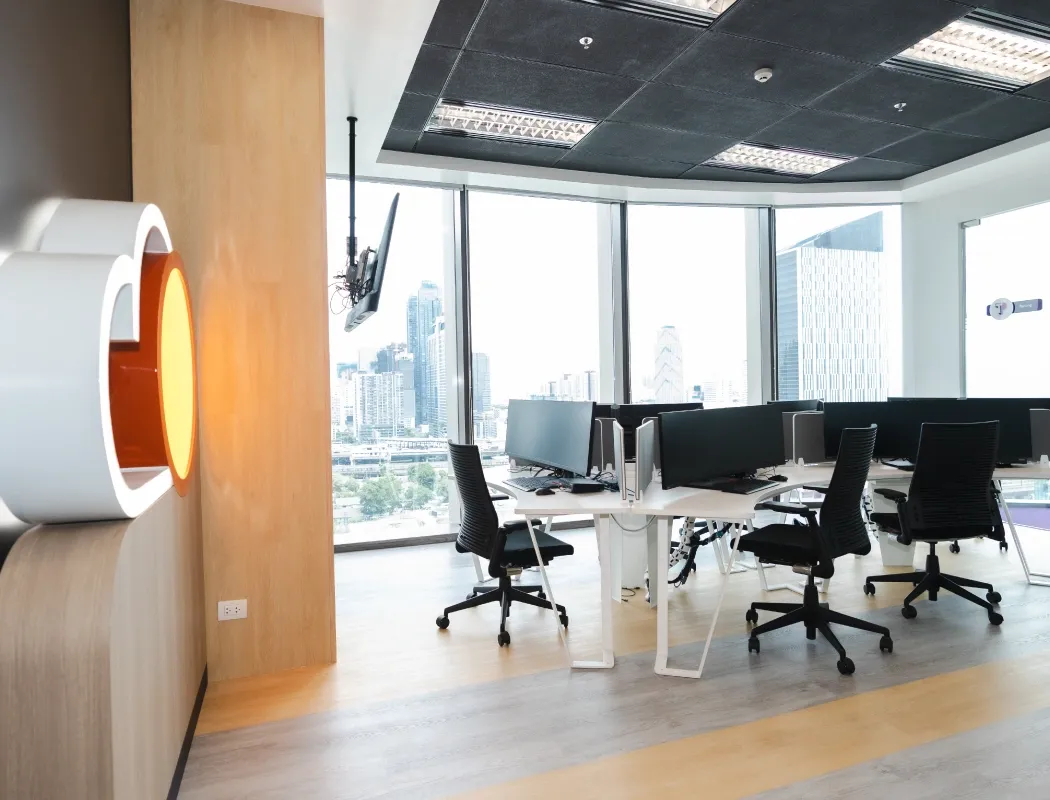 A bright, modern office interior featuring floor-to-ceiling windows offering a stunning panoramic view of the city skyline.