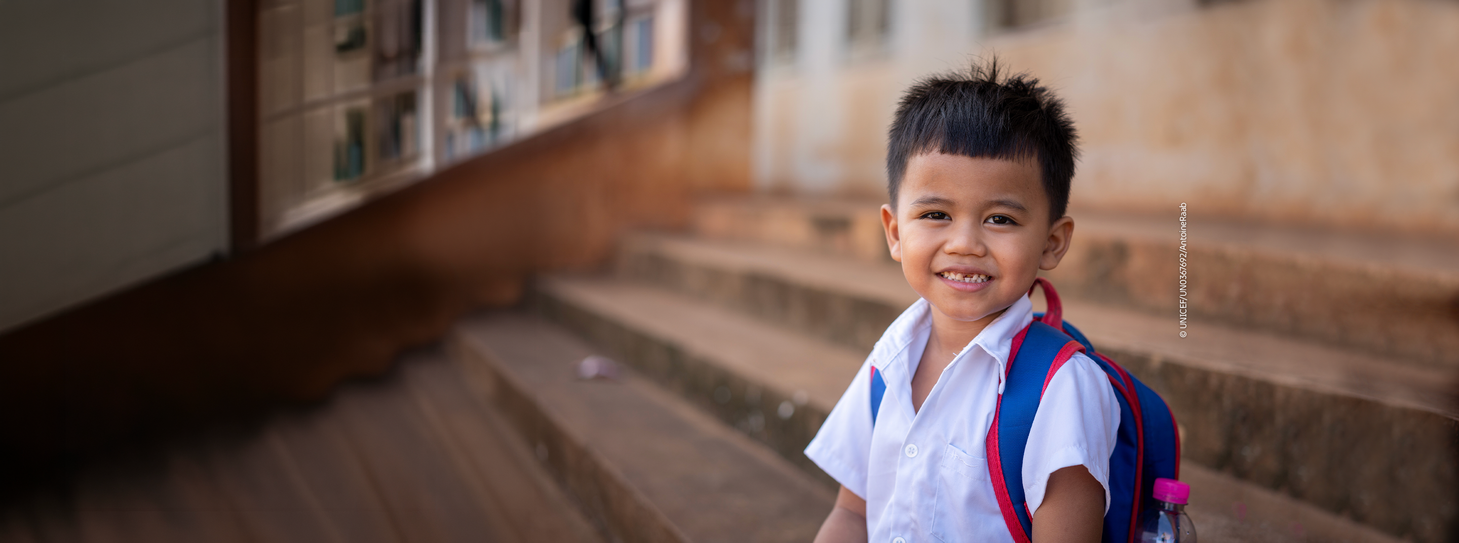 Smiling young boy preparing for school with his backpack.