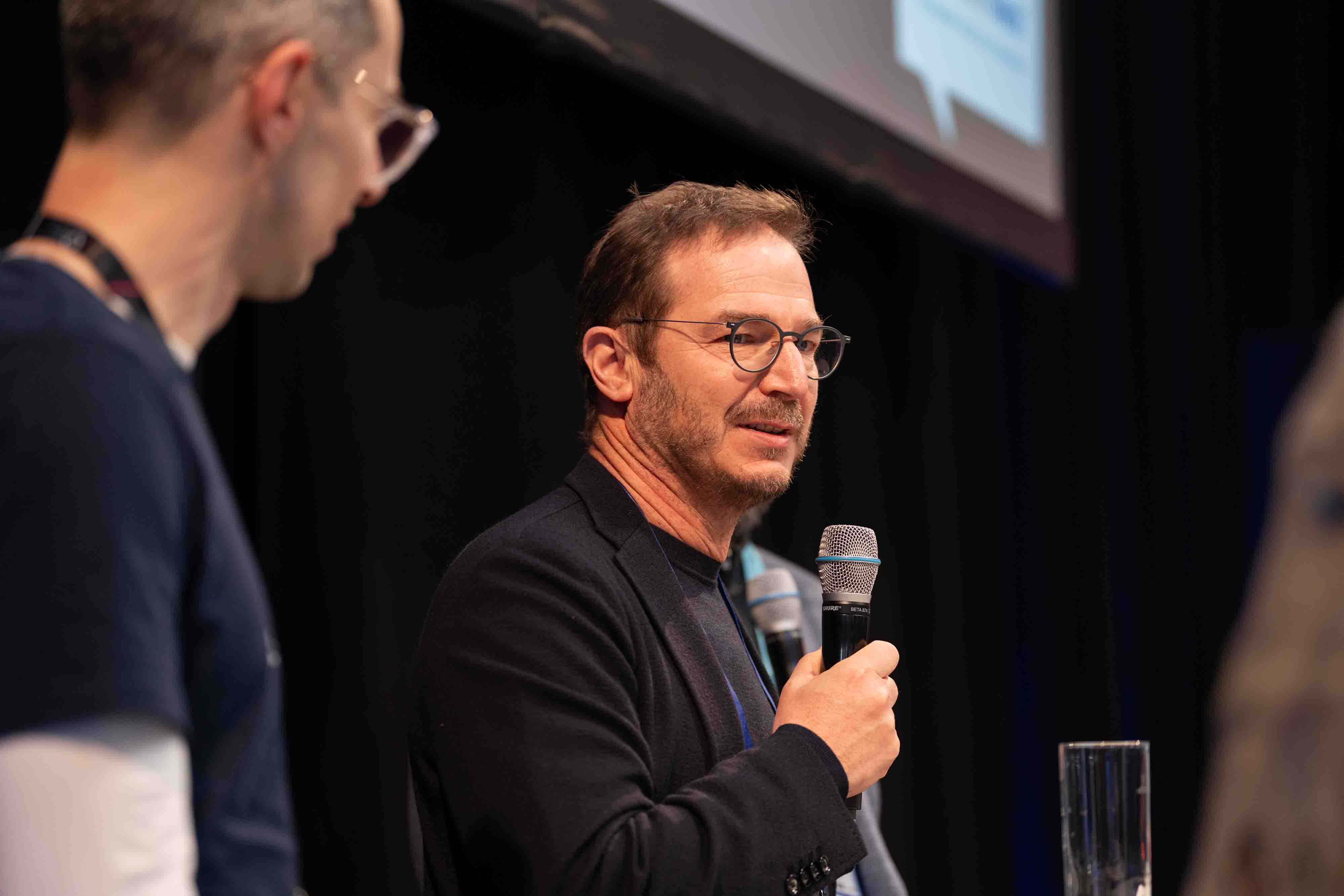 Speaker presenting to an audience during a business conference.