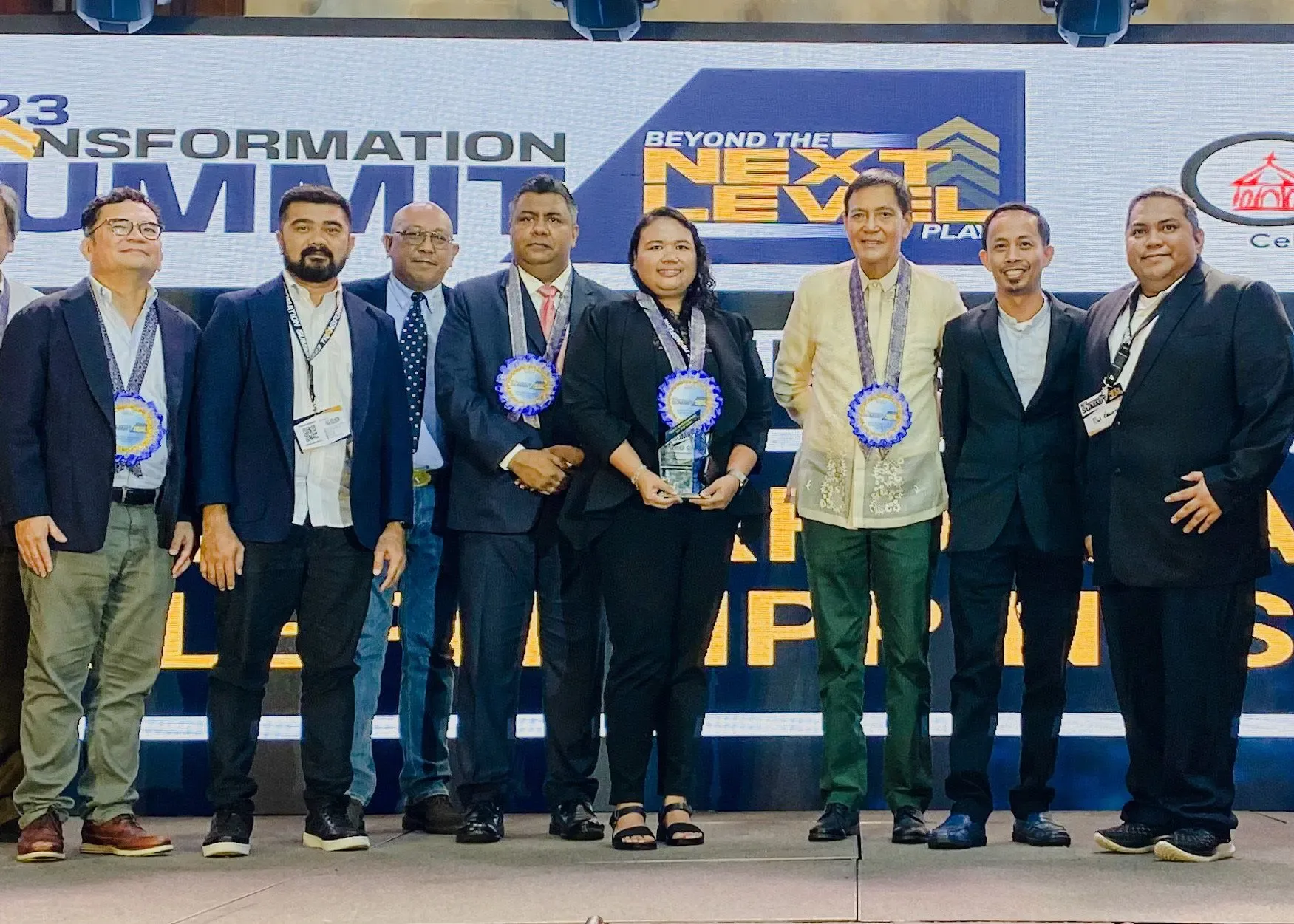 Group of professionals on stage with awards and medallions at the Transformation Summit 2023.