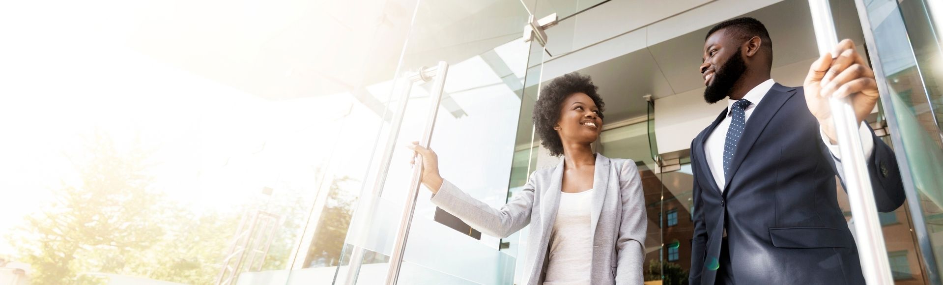 African business couple opening a bright glass door, symbolizing the start of new business opportunities, challenges, and paths to success.