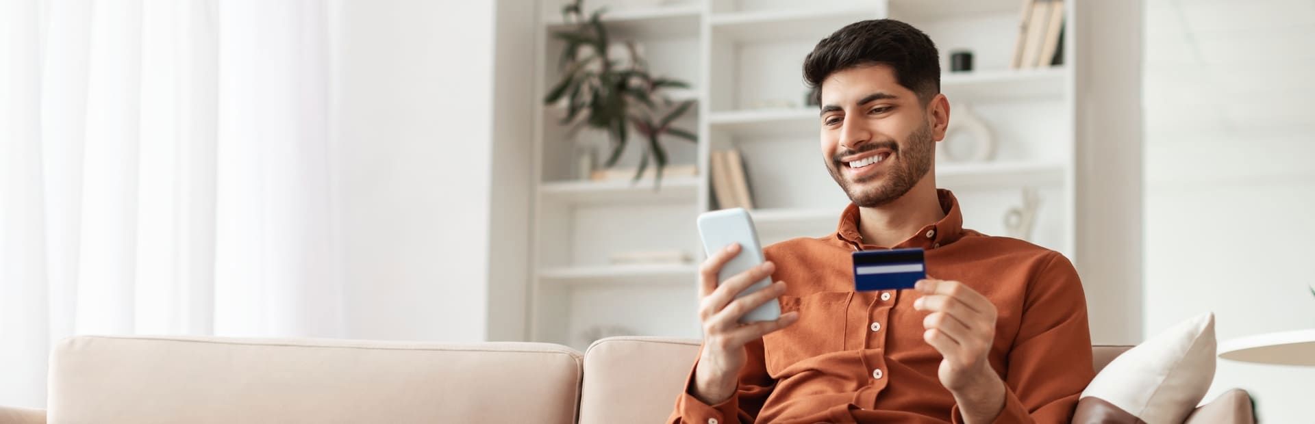 A man holding a credit card and smartphone, illustrating debt recovery services.