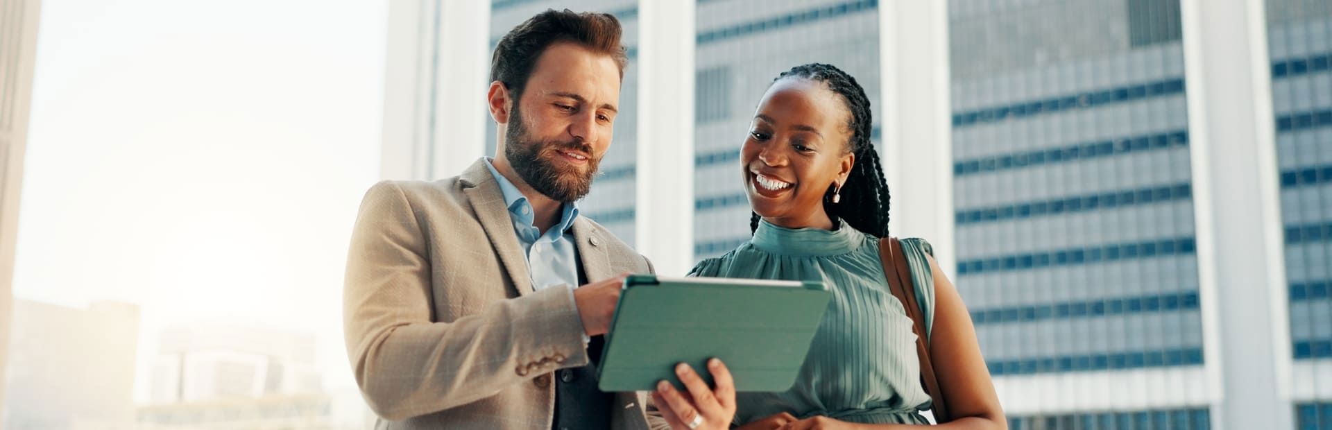Smiling colleagues view a tablet in a modern office, evoking AI and emotional intelligence.