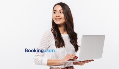 Woman with laptop beside Booking.com logo, highlighting TP’s global customer support solution.
