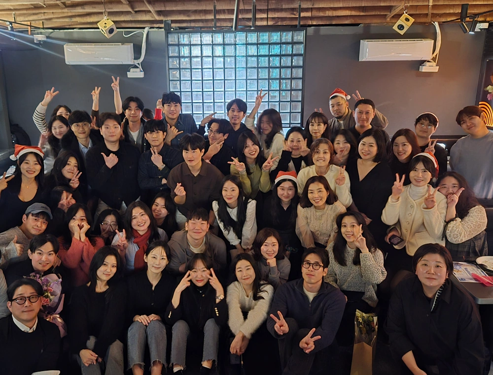 A large team of colleagues pose cheerfully together at a festive holiday gathering.