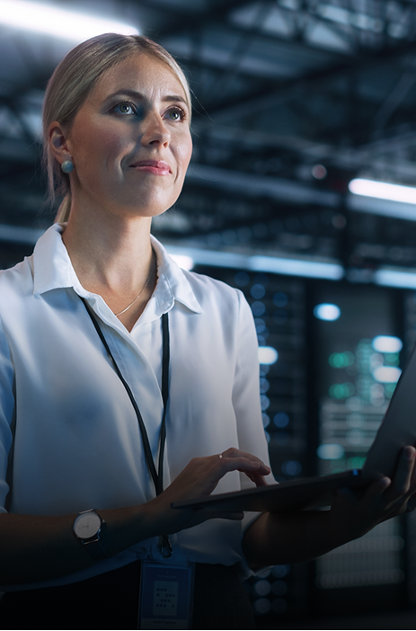 Professional woman using a tablet in a modern data center environment.
