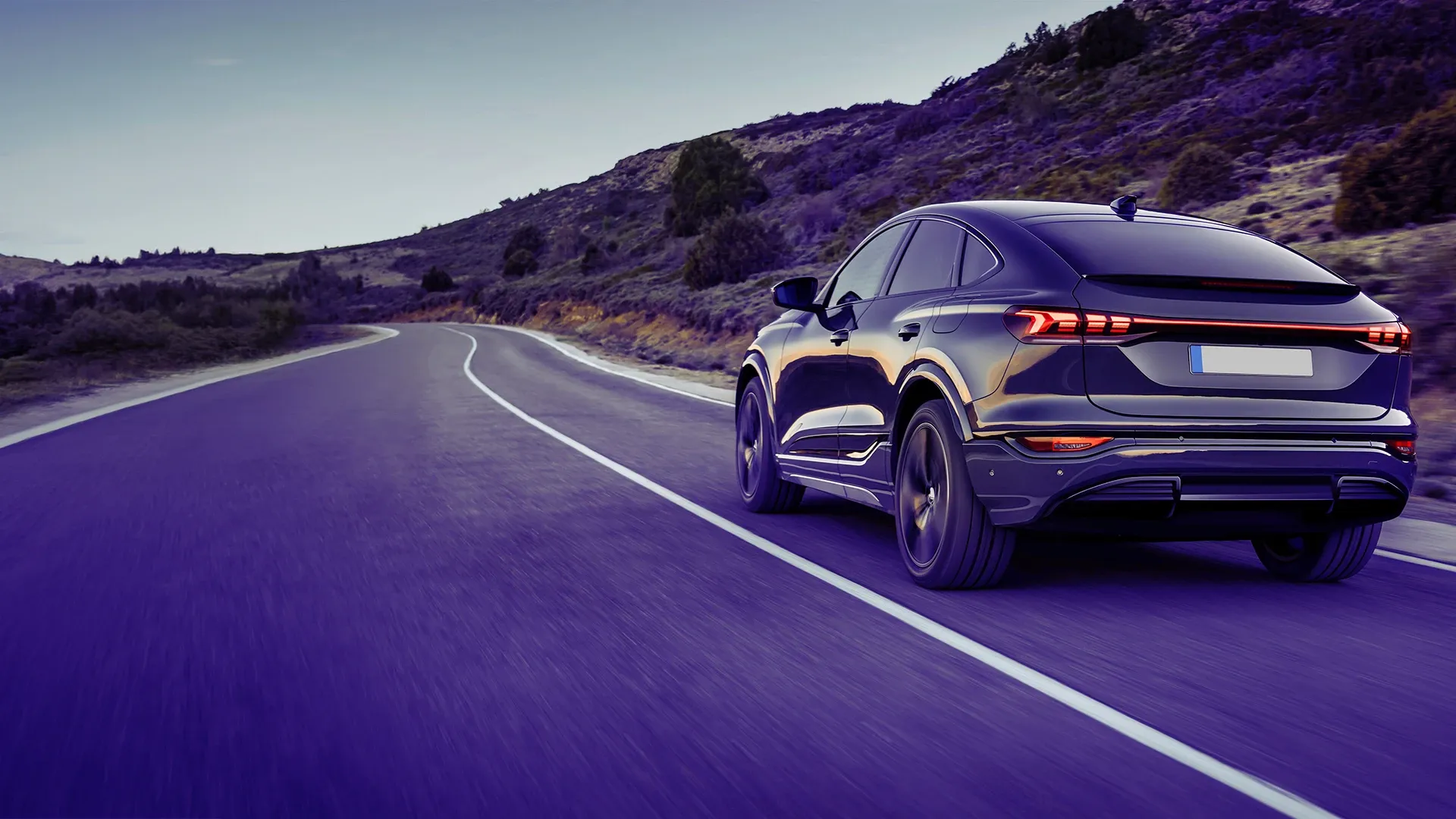 Black modern car driving on a road.