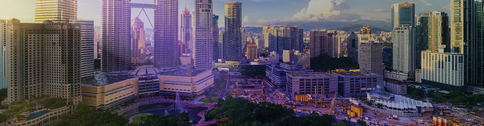 Kuala Lumpur cityscape with modern skyscrapers, parks, and surrounding hills.
