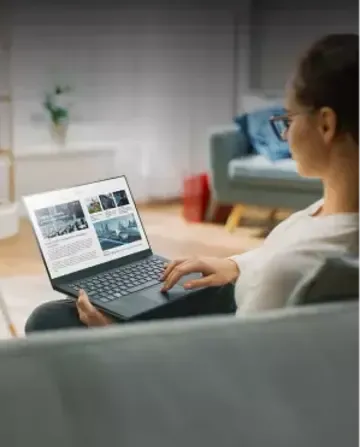 Woman working on a laptop from her sofa at home.