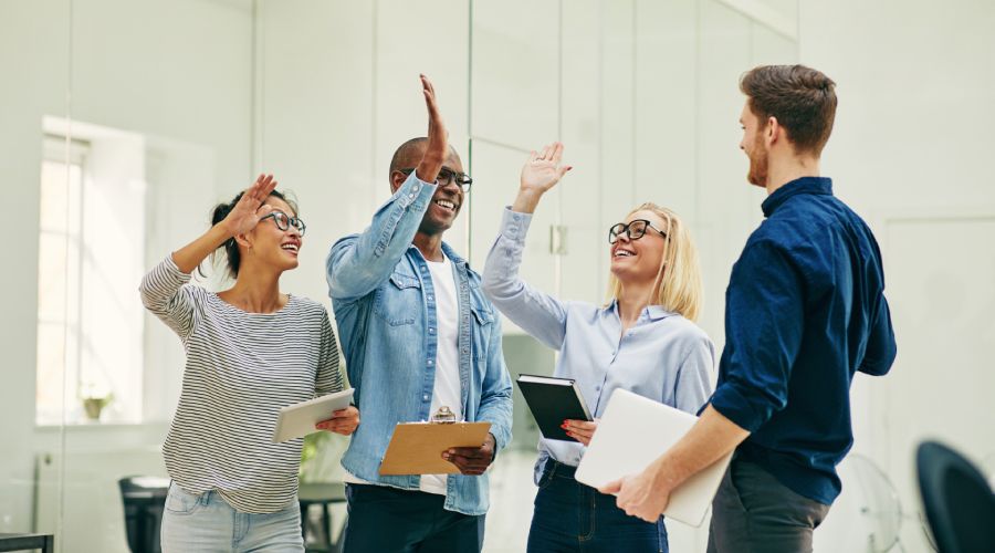 Diverse team celebrating a collective achievement in a professional work environment.