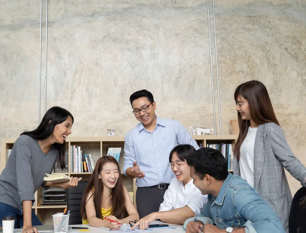 A diverse team collaborates joyfully in a bright, modern office space.