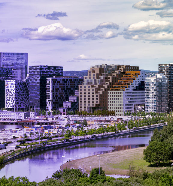 Oslo cityscape with modern buildings, a waterfront, and a riverside park.