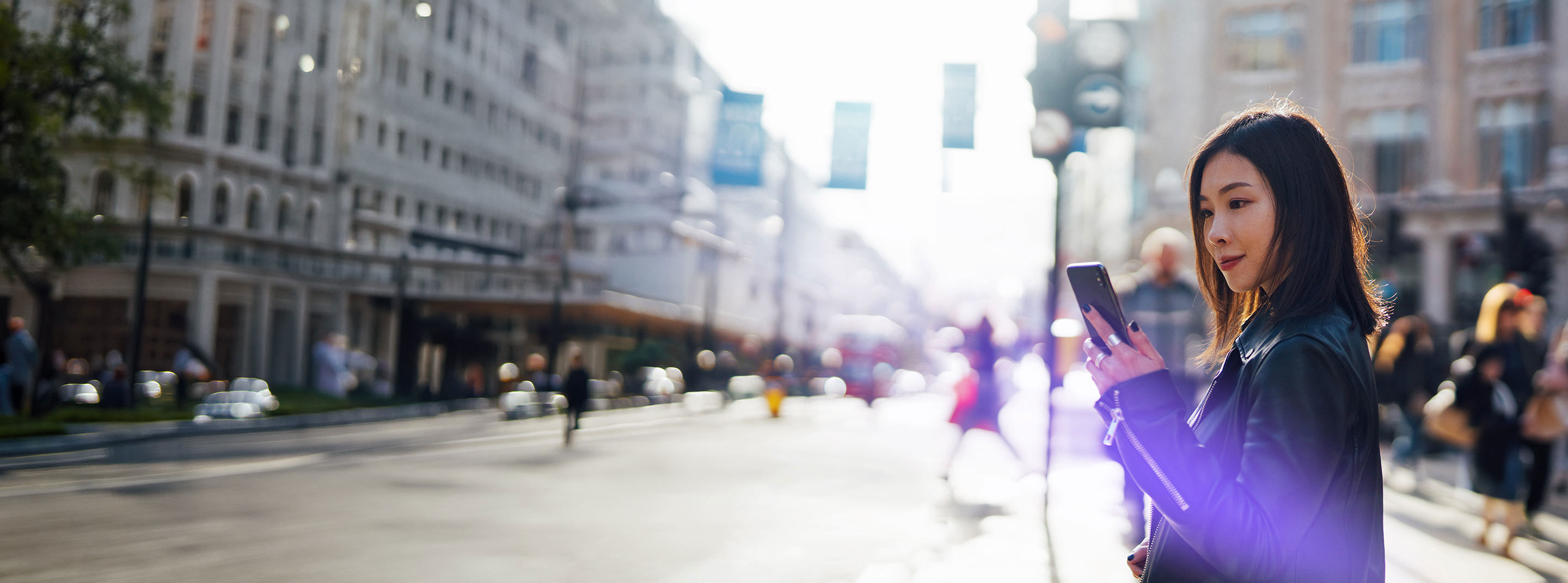 Woman using a smartphone on a city street, representing TP’s smartshoring services.