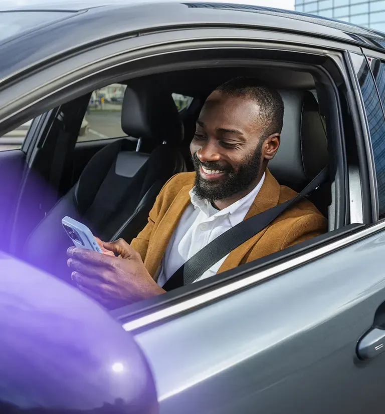 Man using a smartphone while seated in a car, representing TP’s customer experience services.