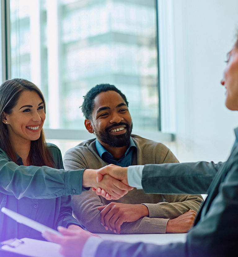 Three professionals discussing recruitment and shaking hands in an office.
