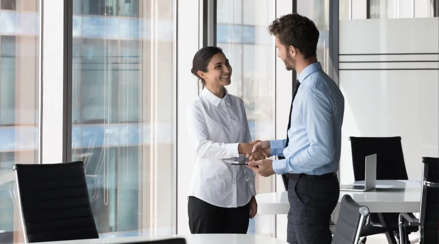 Smiling colleagues shaking hands at the office. 