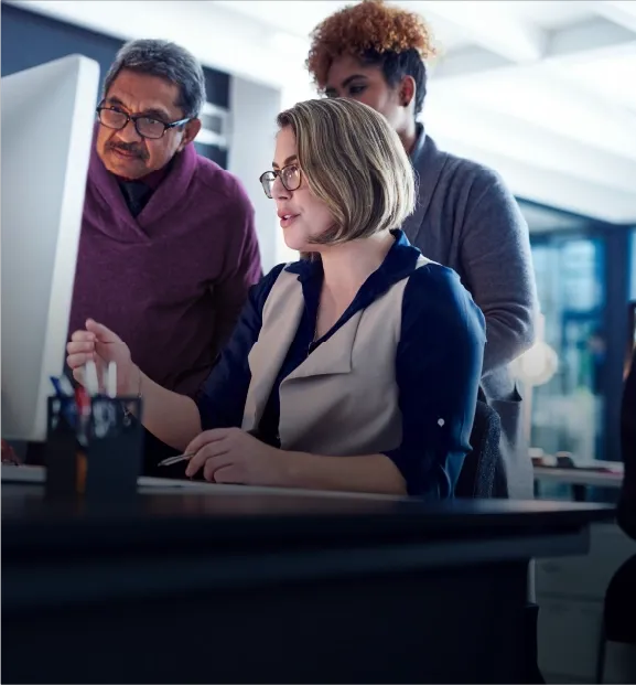 Team reviewing information together on a desktop computer in an office setting.