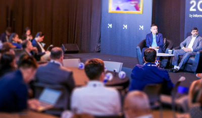 A business panel discussion with speakers on stage and an engaged audience.