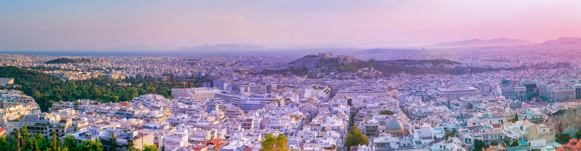 Athens skyline with the Acropolis and surrounding cityscape at sunset.