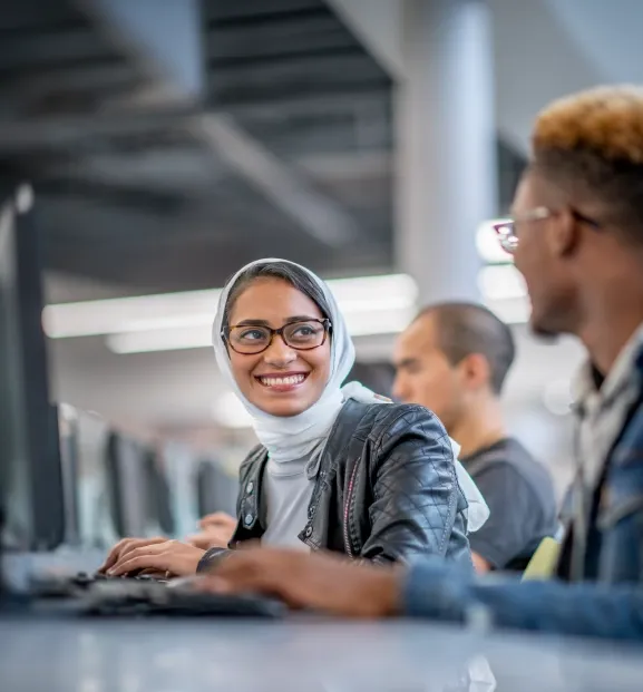 Customer support agents collaborating at computers in a modern contact center.