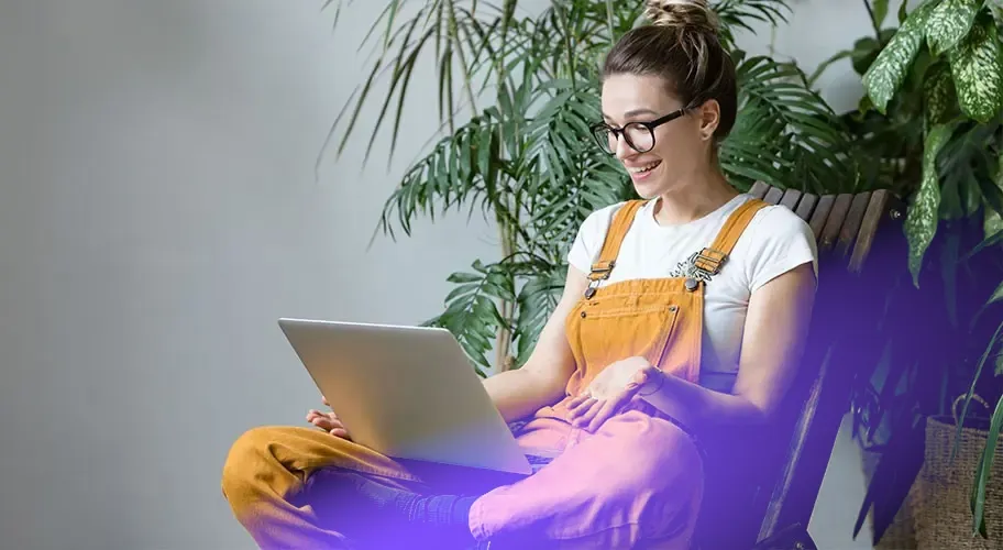 A young woman in comfortable clothes working from home with a laptop on her lap, highlighting the flexibility of work at home.