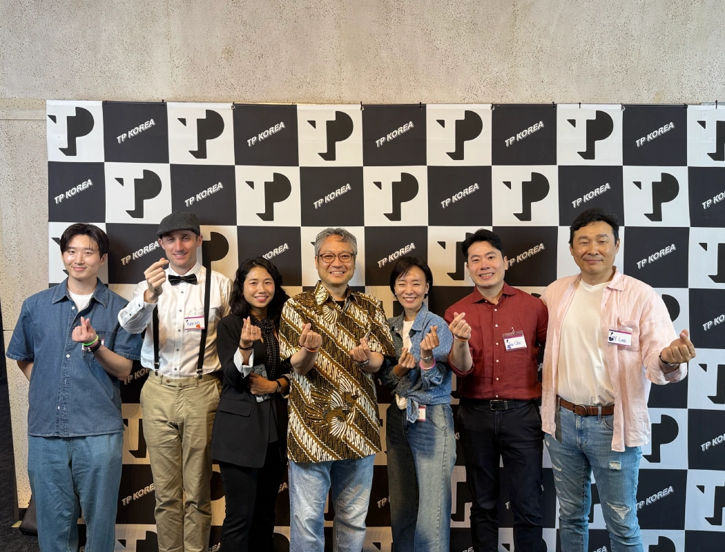 Seven colleagues pose together with matching hand gestures at a TP Korea event.