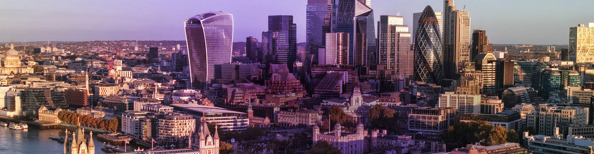Aerial view of the City of London skyline at sunset, with the River Thames and modern skyscrapers. 