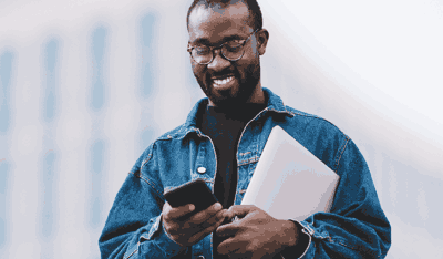 Afro-descendant man using phone and laptop, illustrating a case study on ESAT and CSAT.