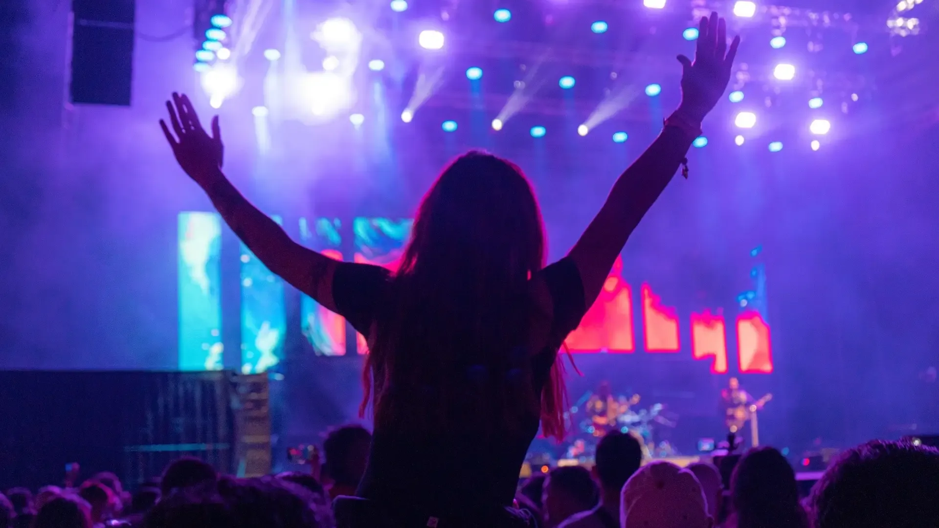 Woman in front of a music stage with her hands up.