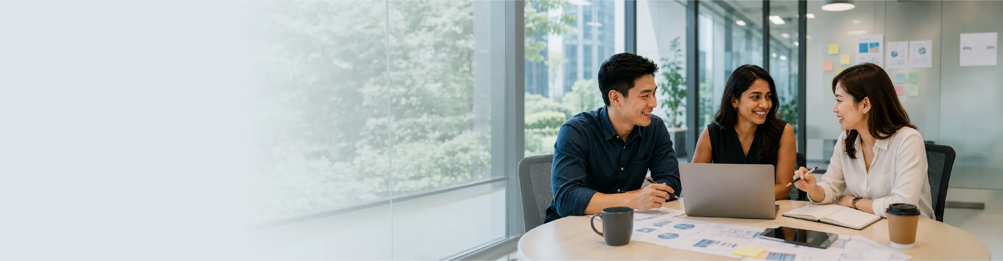 Three diverse colleagues collaborate happily in a bright office meeting