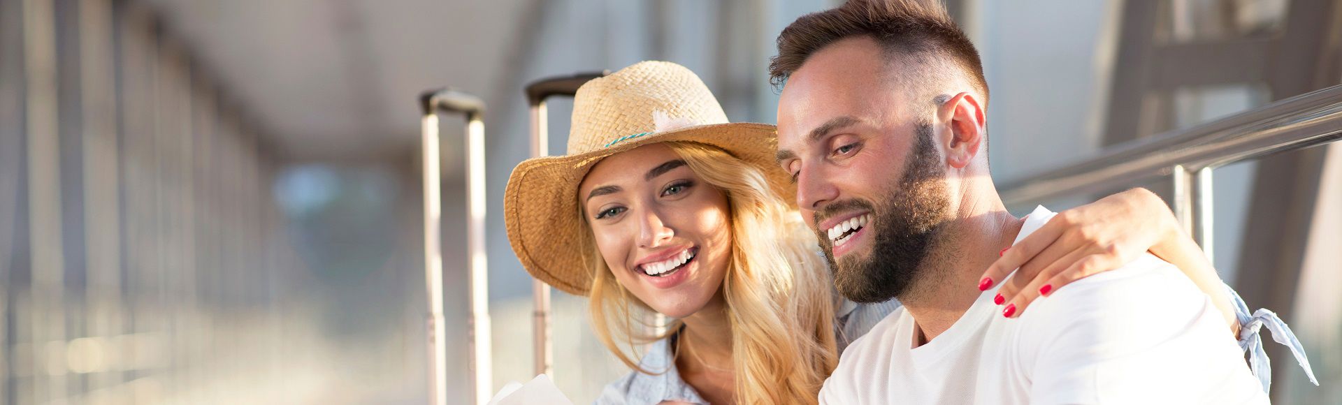 Smiling couple with luggage enjoying a moment together at a travel terminal.