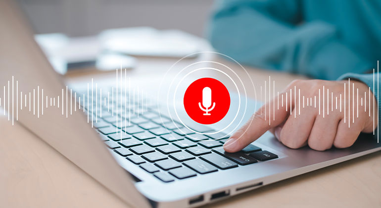 Person using laptop with voice input feature activated, highlighted by red microphone icon and sound wave graphics — illustrating modern voice recognition technology for virtual assistants, transcription, and accessibility tools.