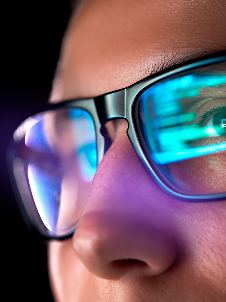 Programmer's eyes reflecting code displayed on a laptop screen.