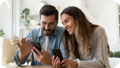 Smiling couple sit together at home and browsing smartphone