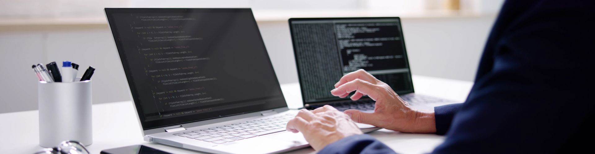 Person coding on two laptops, representing TP’s work with Agentic AI and advanced tech.