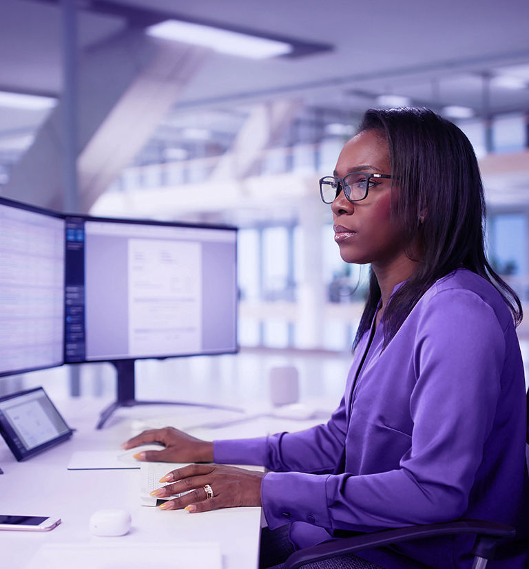 Afro-descendant professional monitoring multiple screens in a high-tech security environment.