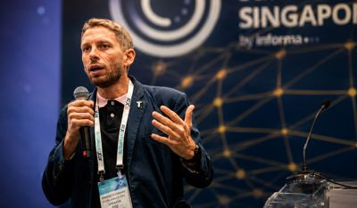 A speaker delivers a keynote at The AI Summit Singapore to a large audience.