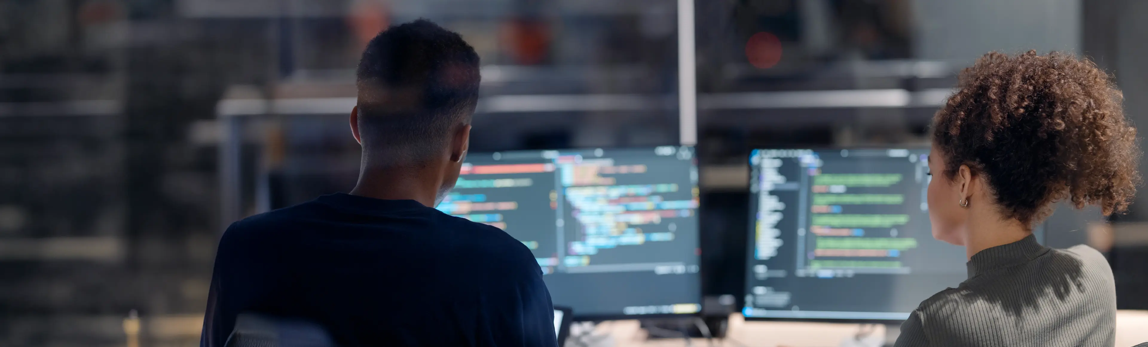 TP team reviewing code on multiple monitors in a collaborative workspace.