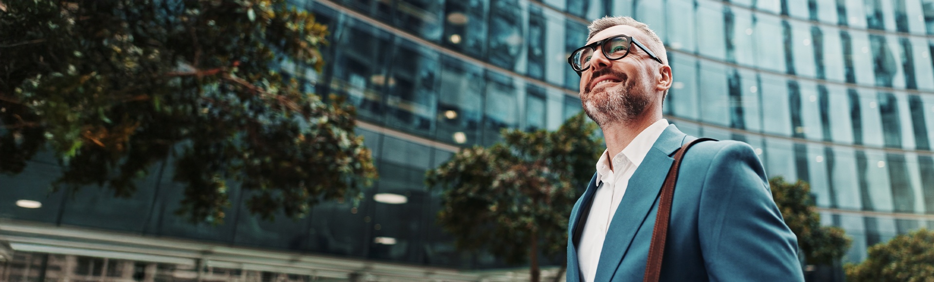 Businessman from the banking sector walking confidently past modern glass office buildings.
