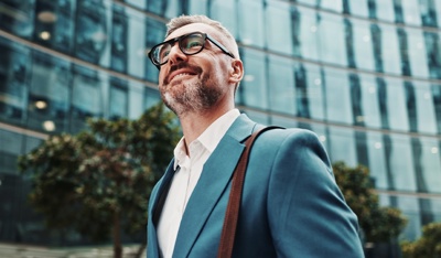 Businessman from the banking sector walking confidently past modern glass office buildings.