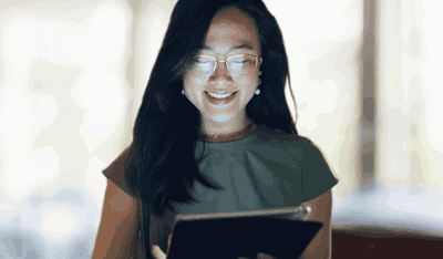 Smiling Asian woman browsing her tablet, illustrating a client story on AI-powered transformation.