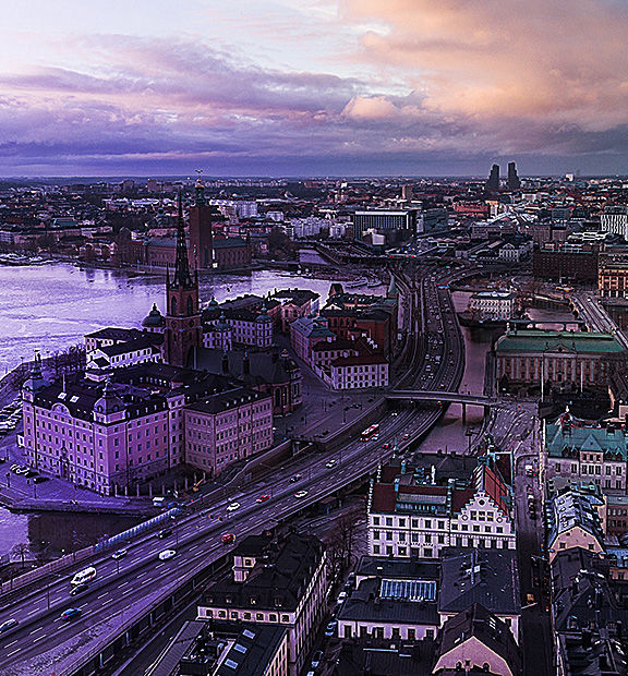 Aerial view of Stockholm, Sweden, with waterways, historic spires, and city buildings under a dramatic twilight sky.