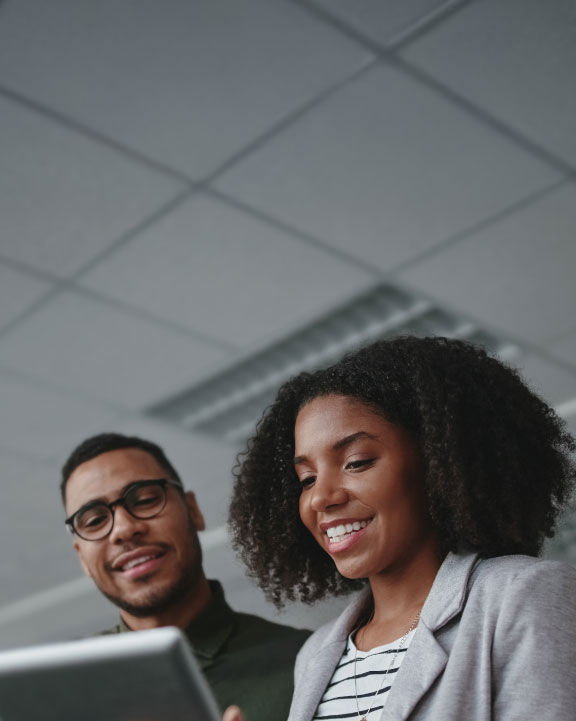 Two young African professionals working on a tablet in a white ceiling office