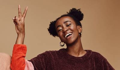 Two cheerful girls smiling and gesturing with their hands towards the camera