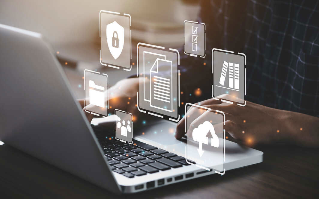 Person typing on a laptop with floating digital icons representing cybersecurity, cloud storage, documents, folders, and data management.