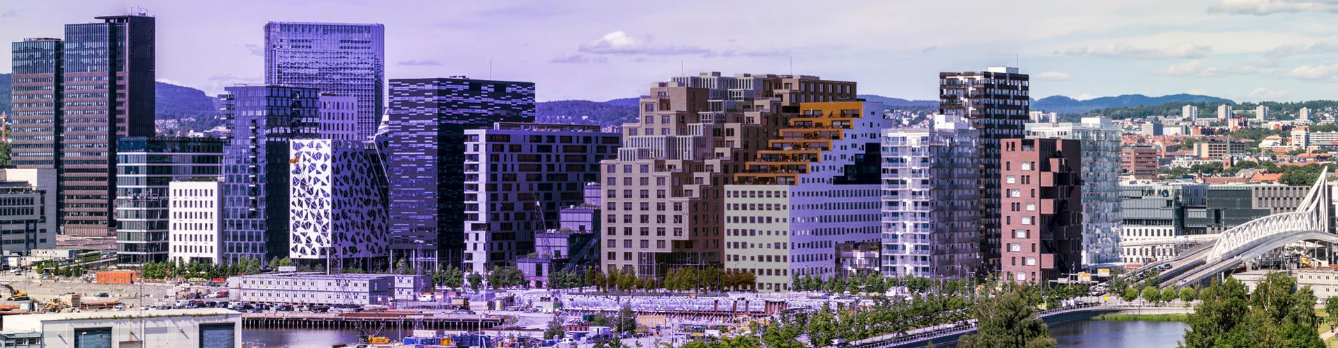Oslo cityscape with modern buildings, a waterfront, and a riverside park.